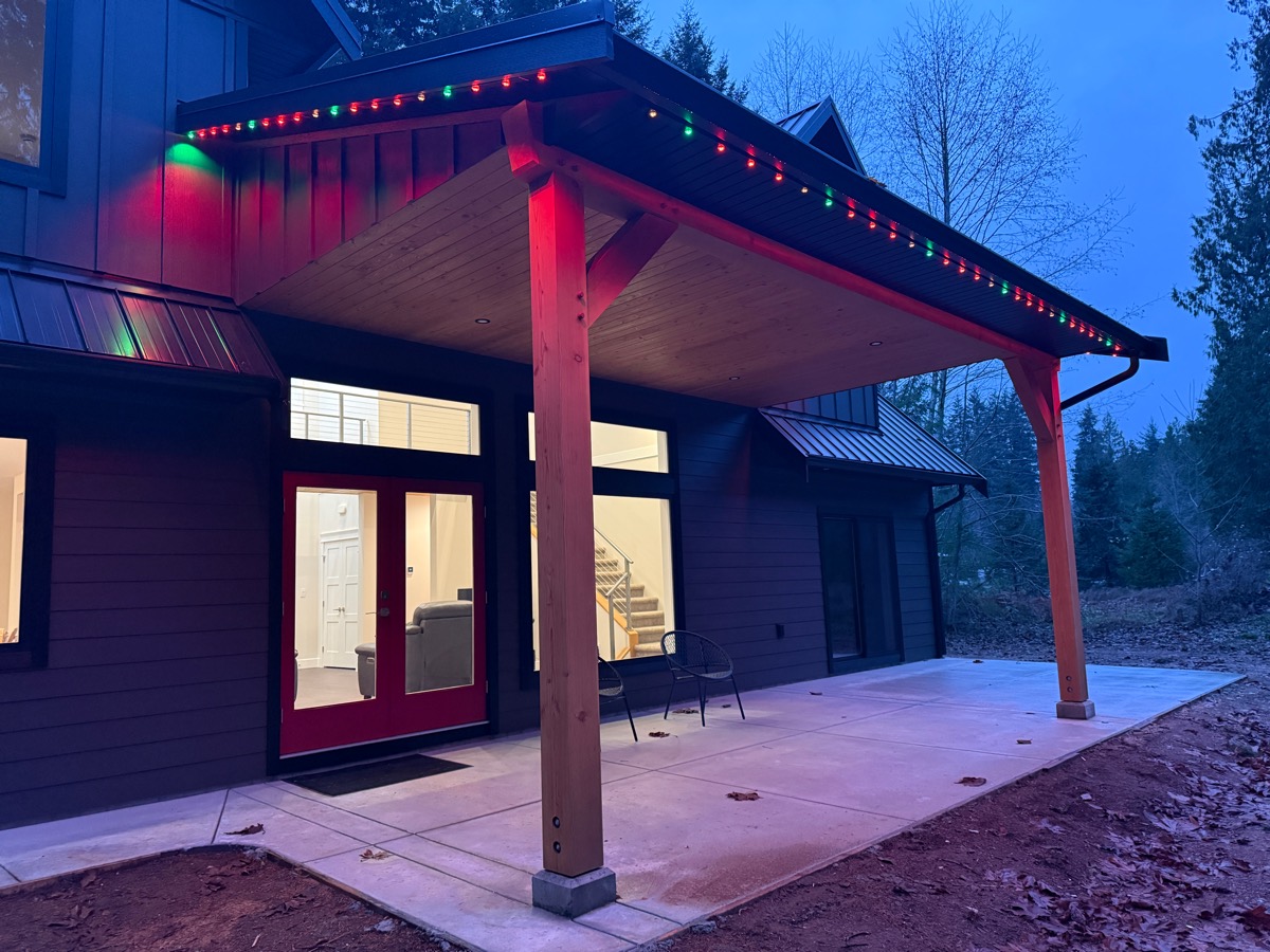 Gemstone Lights along a covered patio roofline, set to red and green at dusk.