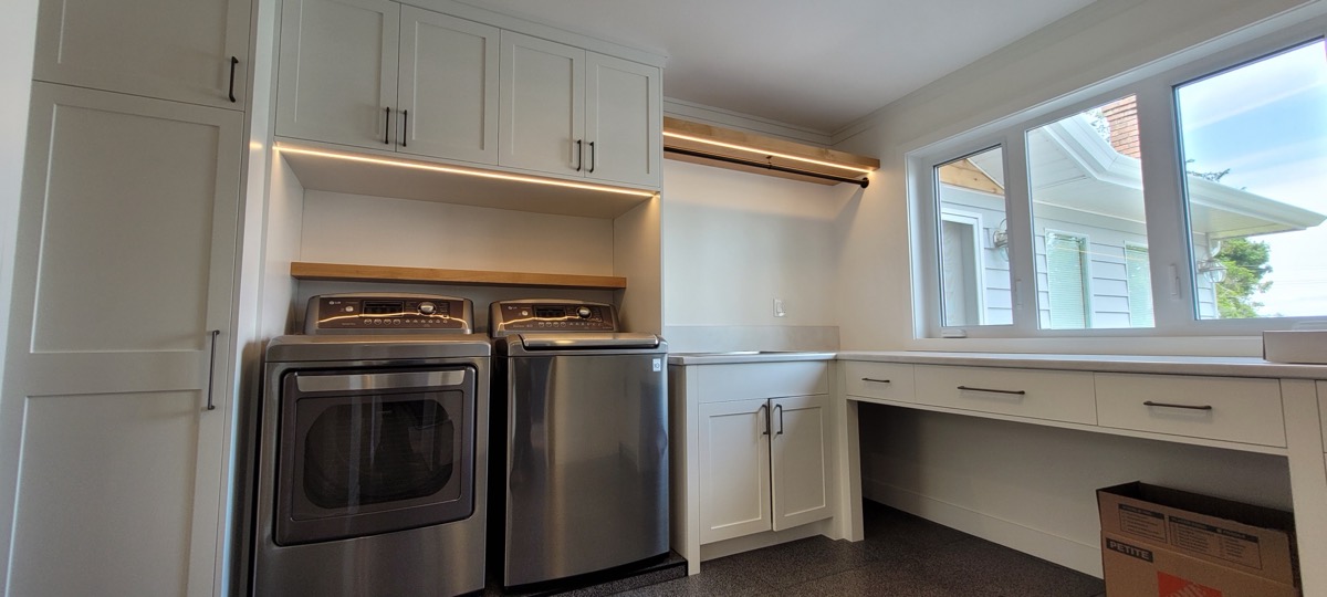 Under-cabinet LED lighting in a renovated laundry room with a built-in desk.