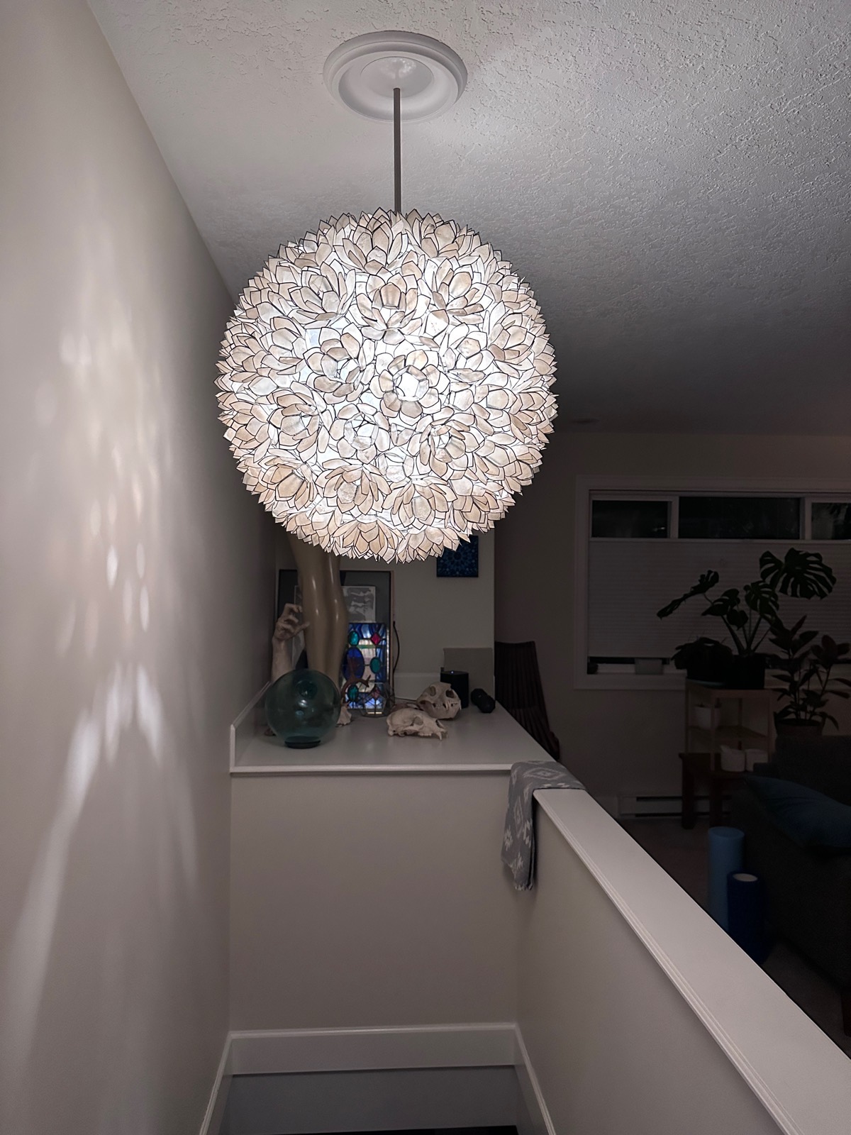 A capiz shell globe pendant lighting a stairwell landing.