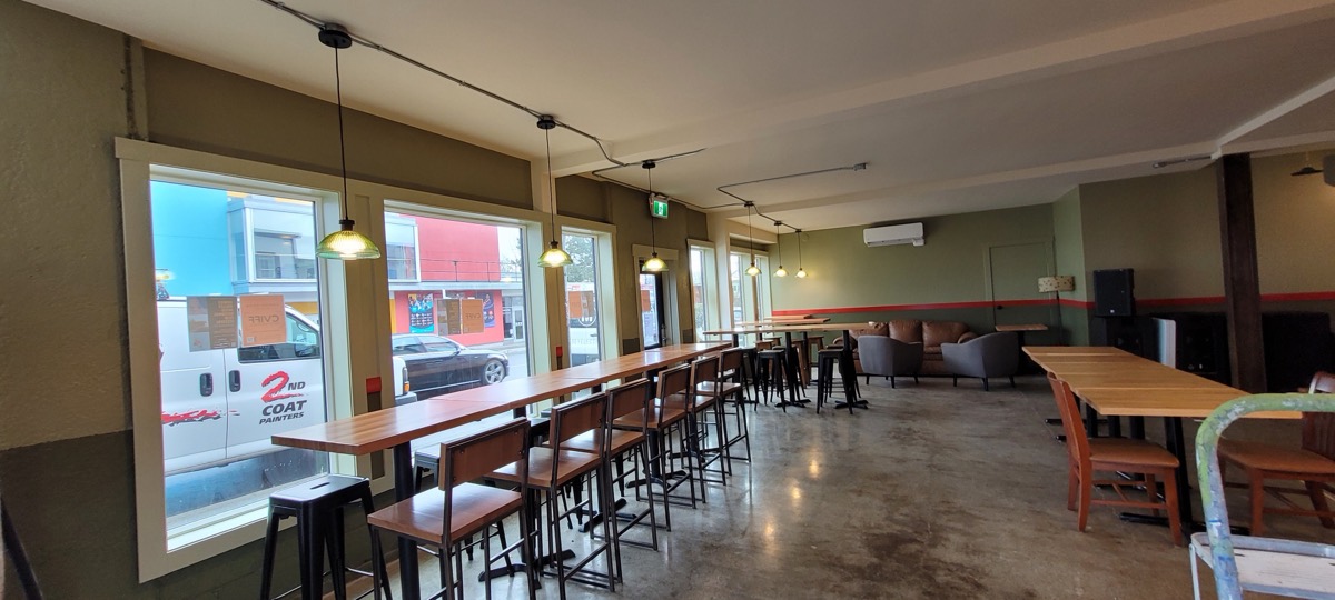 A taproom with new pendant and track lighting over long tables.