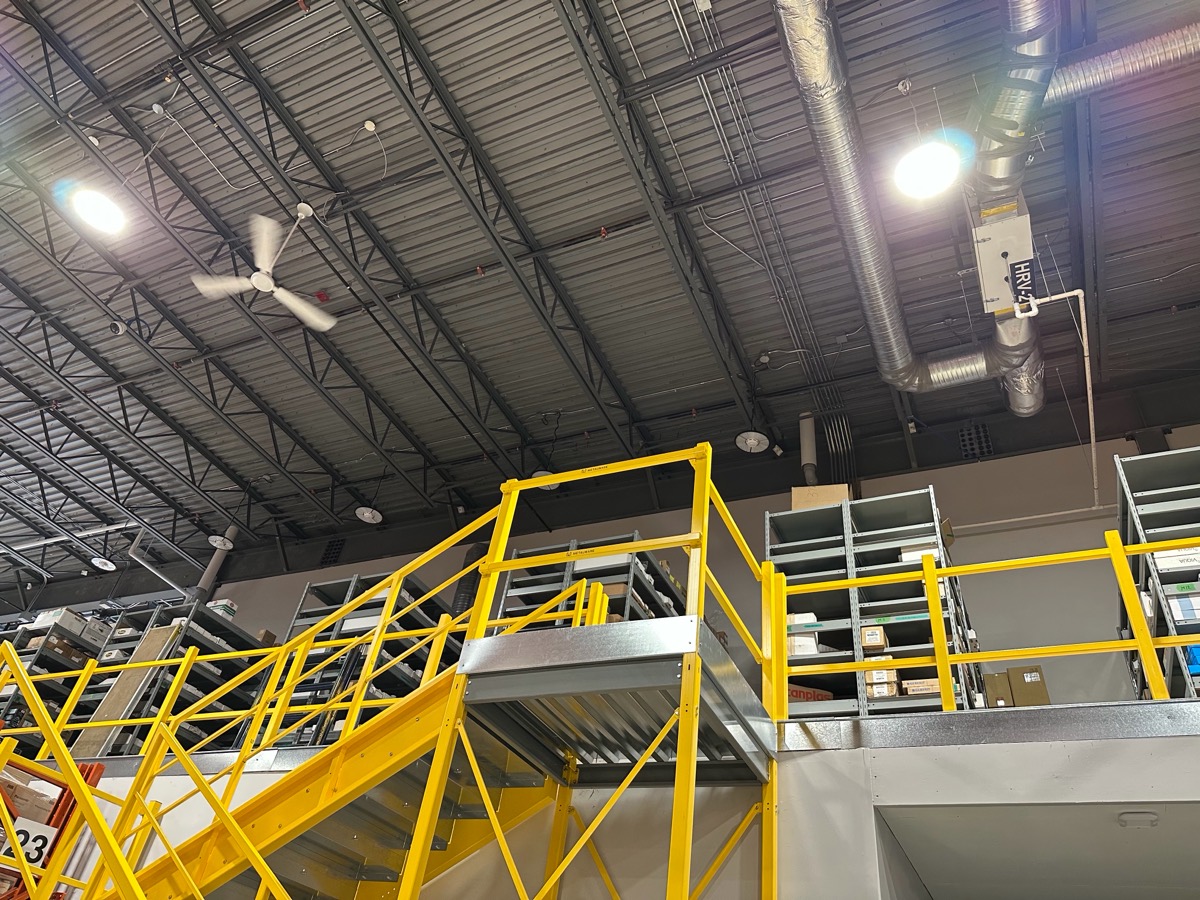 LED high-bay fixtures over a warehouse mezzanine and stairs.