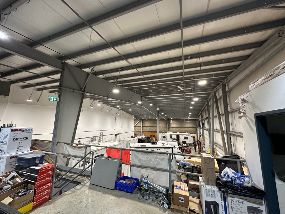 Rows of new LED high-bay fixtures over a warehouse and its shop floor.