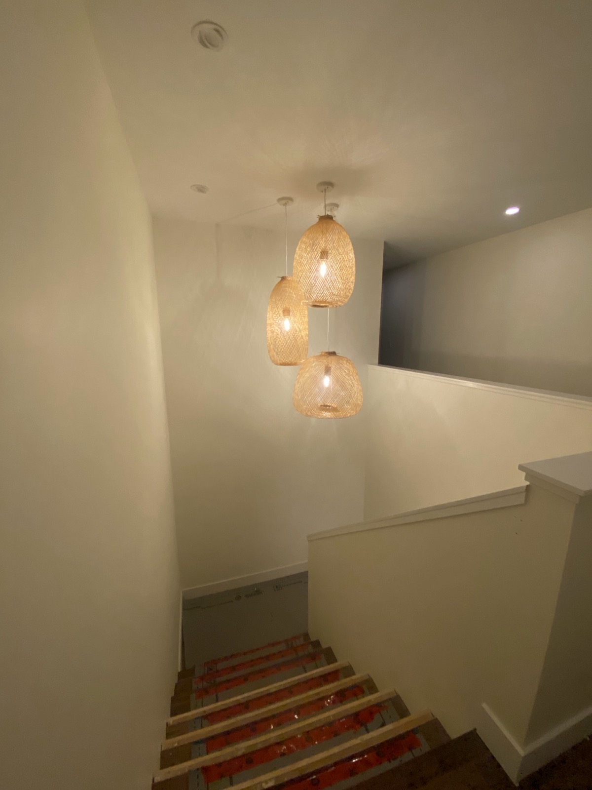Three woven pendant lights hung in a cluster over a stairwell.